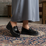 Mocassin noir verni sans métal avec jellaba grise sur tapis marocain