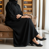 Woman in black djellaba on sofa edge wearing 570F Nawar ballerinas