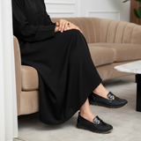 Woman in black matte djellaba sitting on modern velvet sofa wearing 611F Pelta Noir NV