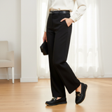 Woman in black trousers and ivory blouse in modern interior wearing 611F Pelta Noir NV