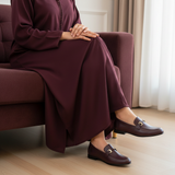Woman in burgundy plum matte djellaba sitting gracefully with soft daylight wearing 447f Candy Grenat loafers