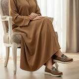 Woman in camel djellaba sitting in armchair wearing 490F Zahir loafers