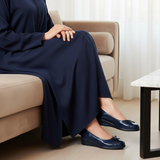 Woman in navy matte djellaba sitting on modern velvet sofa wearing 196F Labelle Bleu Marine