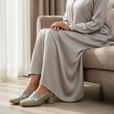 Woman in silver matte djellaba sitting gracefully with soft daylight wearing 157F Bayan Doré loafers